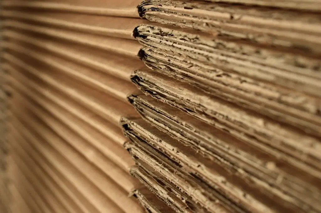 Close-up view of a stack of corrugated cardboard sheets showing the layered edges aligned in a row, ready for packing — perfect for anyone moving in Edinburgh or needing a man with a van for hire.