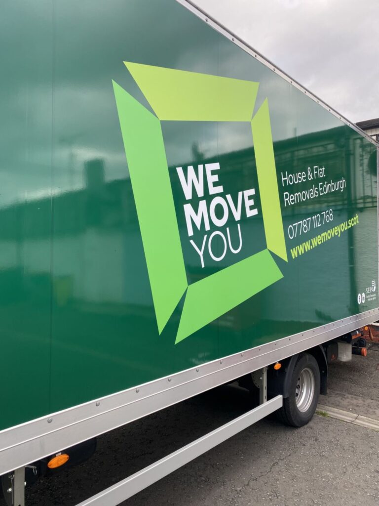 A green moving truck for hire with "We Move You" and contact details for house and flat removals in Edinburgh displayed on its side.